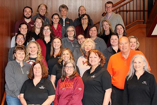 28 members of the staff of Career and Professional Development in a group photo taken on the staircase at The Inn at Virginia Tech in January 2023.